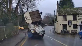 Small lorry carrying a crushed van and trailer, strapped precariously to the back of it.