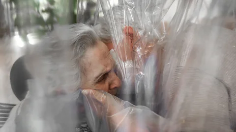 People hugging through a plastic sheet in room in Italian care home in November 2020 (Credit: Max Cavallari)