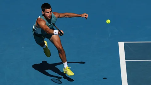 Carlos Alcaraz jumps to return a ball with his tennis racket (Credit: Getty Images)