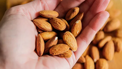Hand holding a handful of almonds (Credit: Getty Images)