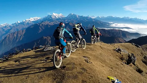 Four mountain bikers bike on top of a mountain in the Himalayas (Credit: Phaplu Mountain Bike Club)