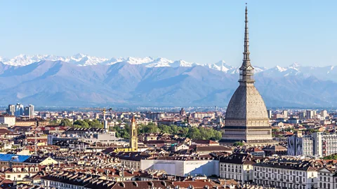 Getty Images Turin's city skyline with the Mole Antonelliana rising above historic rooftops, with the Alps in the background (Credit: Getty Images)