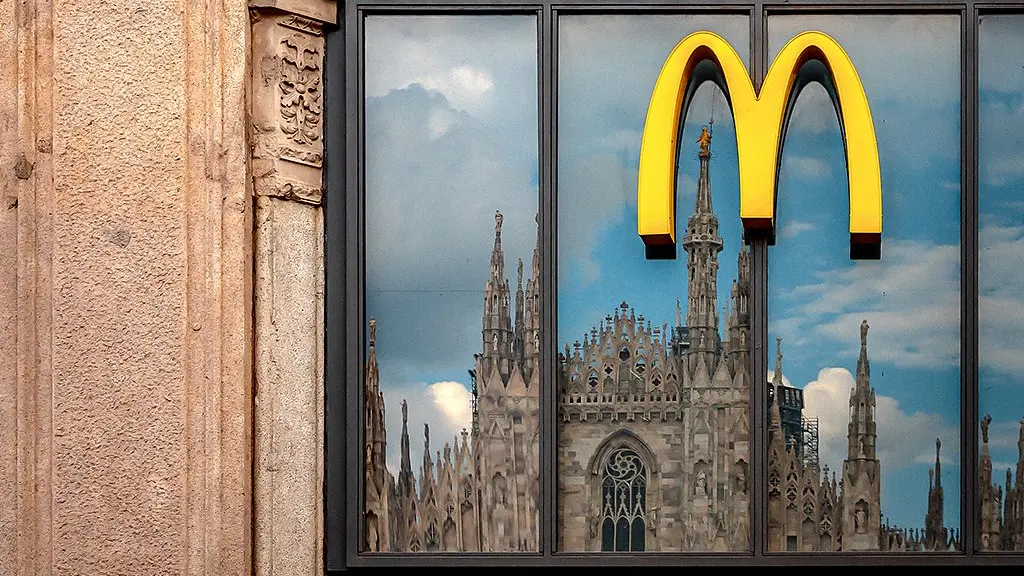 Night view of McDonald's lit up in blue and purple lights with Kuwait Towers glowing green and red in background (Credit: Gary He/McAtlas)