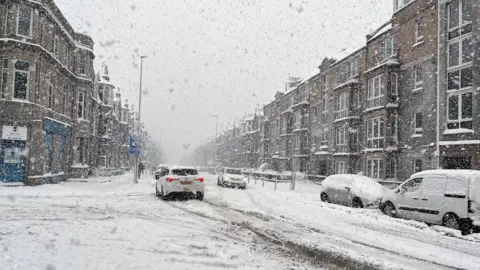 Big flakes of snow fall on a snow-covered street in Inverness on 5 January this year.