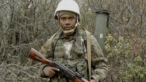 Ukraine Defence Intelligence Clinton Nyapara Mogesa, in military uniform, holding a rifle 