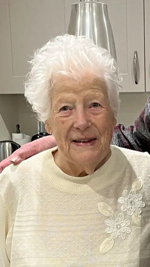 An elderly woman in a yellow top.