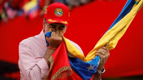 Venezuela's President Nicolas Maduro kisses a Venezuelan flag during a ceremony to swear in new community-based organisations
