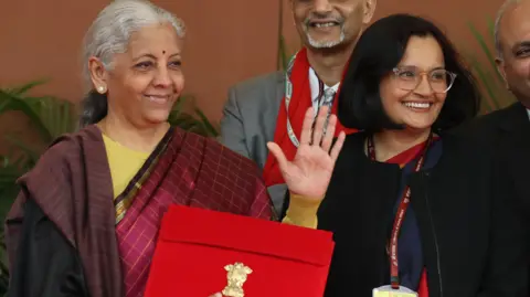 EPA India's Finance Minister Nirmala Sitharaman (R) leaves the Finance Ministry office to present the annual budget to the parliament wearing a traditional Indian saree and carrying a red briefcase with the budget documents. She is surrounded by government officials. Photo by RAJAT GUPTA/EPA/Shutterstock