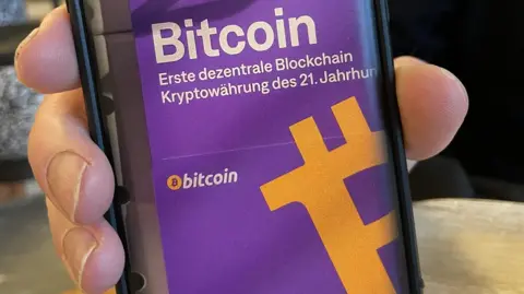 A man showing an app on his mobile phone that allows him to pay in bitcoin