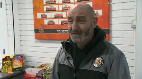 Lee stands in the clubhouse talking to the camera.