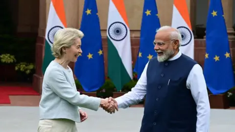 Indian Prime Minister Narendra Modi shakes hands with European Commission President Ursula von der Leyen at Hyderabad House in Delhi on 28 February, 2025, with EU and India flags in the background. 