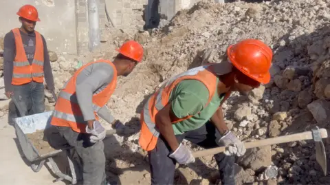 Palestinian workers clear rubble from the courtyard of the partially-destroyed Great Omari Mosque in Gaza City, northern Gaza