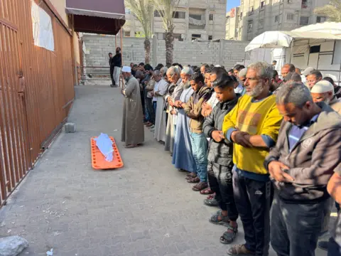 A large group of Palestinians stand in prayer at the funeral of Palestinian boy Saadi Abu Taha