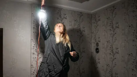 Yulia hangs a light in her home