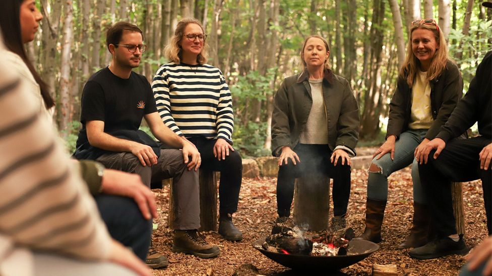 Group of people sitting on logs around a fire in the woods (Credit: Birling Estate)